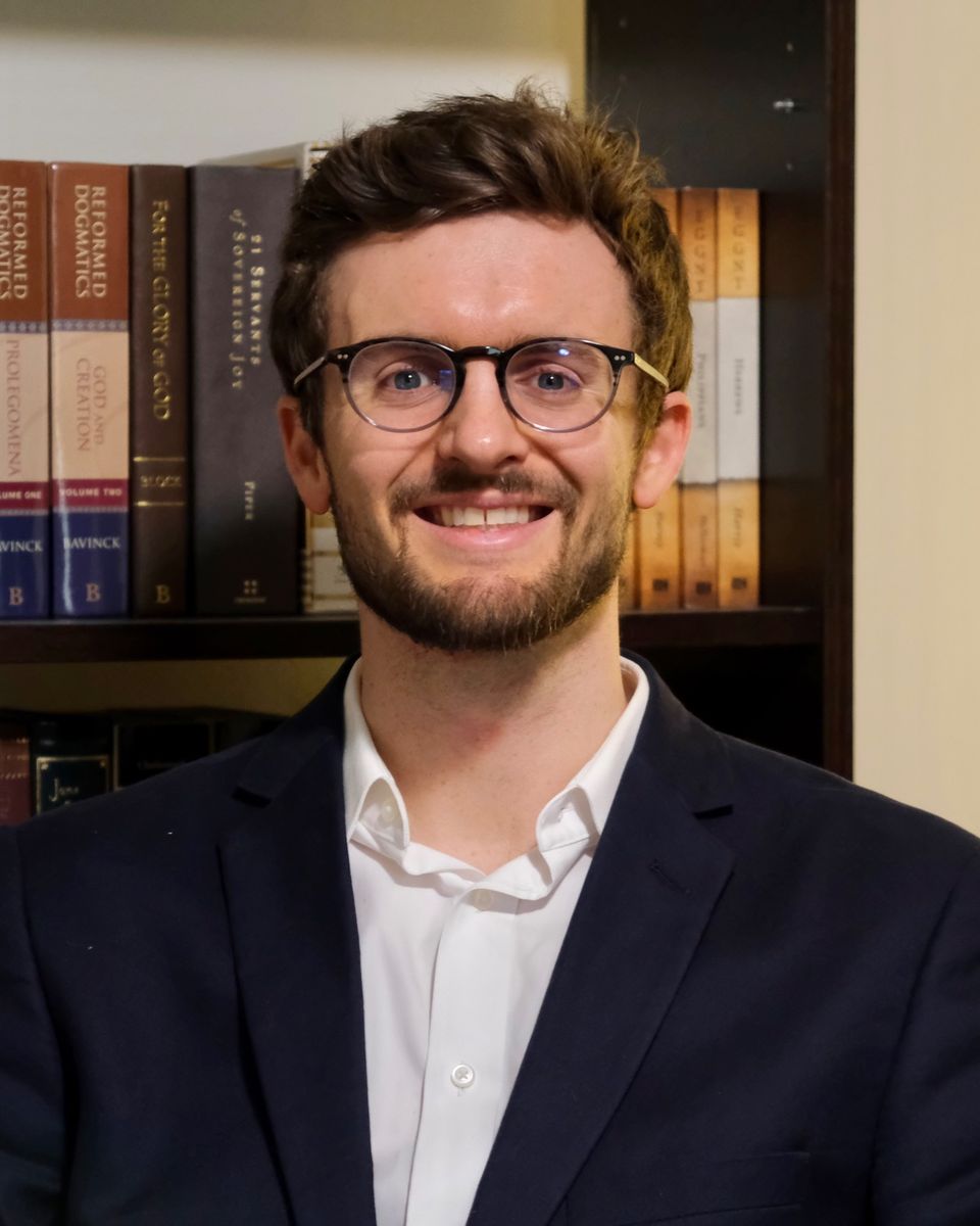 Sawyer D. Moranville smiling in front of a bookshelf